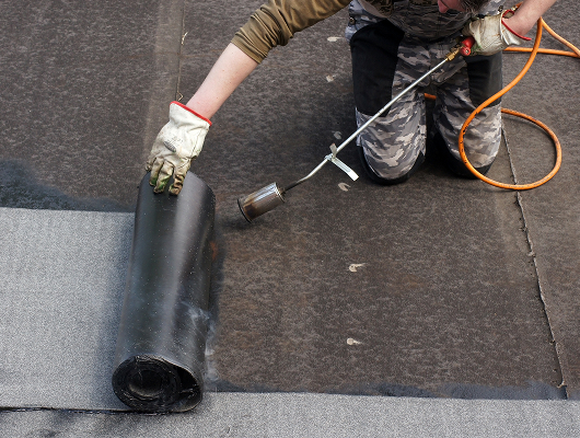 Worker installing torch-on membrane during roof waterproofing in Singapore