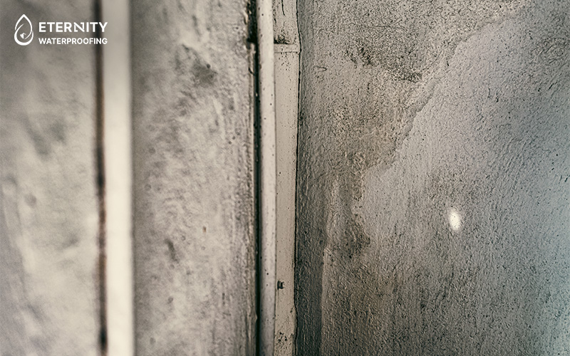 Close-up of a rough wall corner with white trim between two textured surfaces.