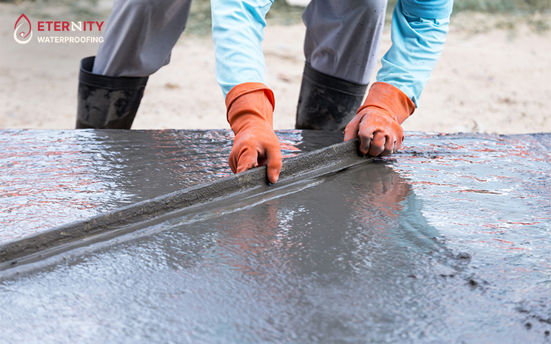 Person smoothing wet concrete with a straightedge tool.