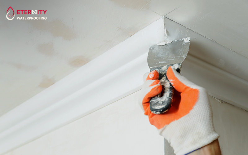 A worker applying plaster to a ceiling cornice